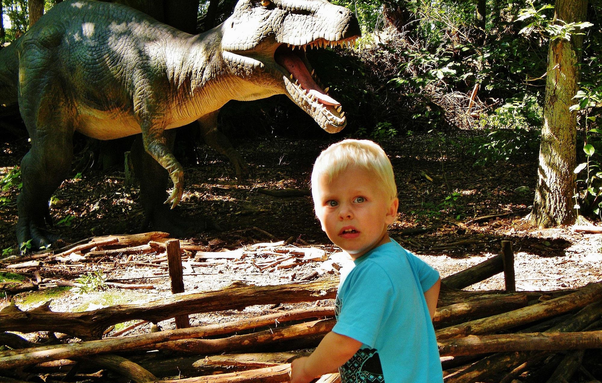 Scared boy in the park seeing a dinosaur 