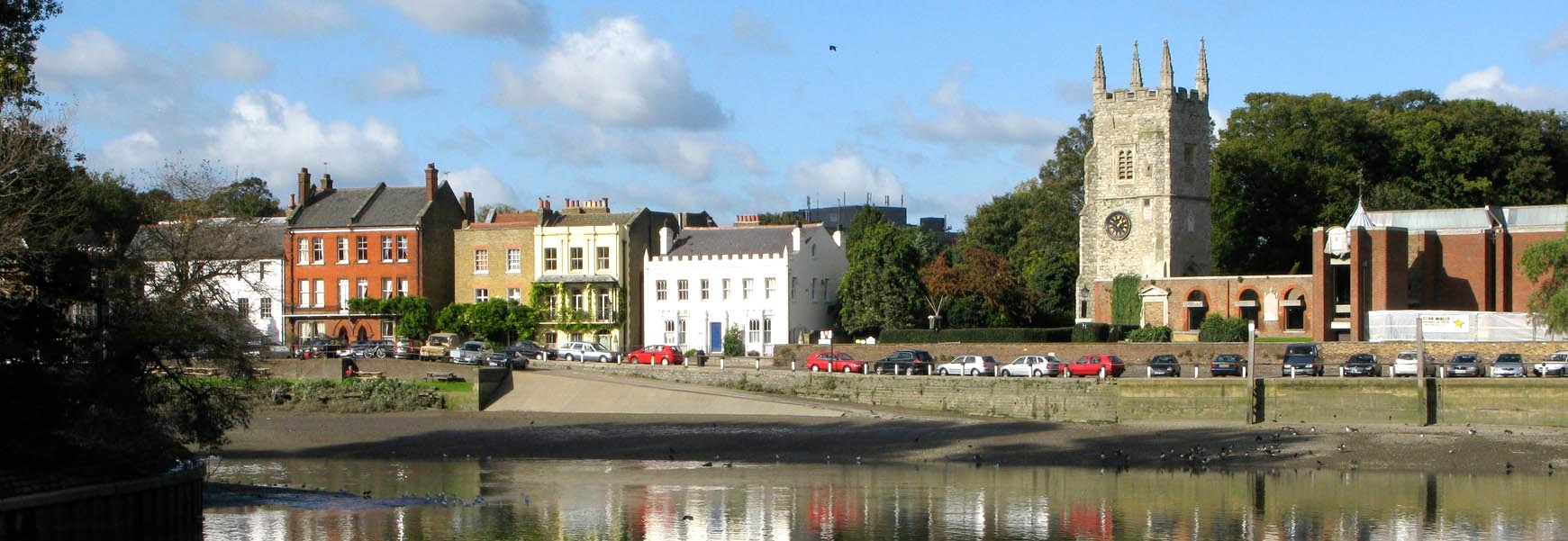 Little houses by the river and many parked cars