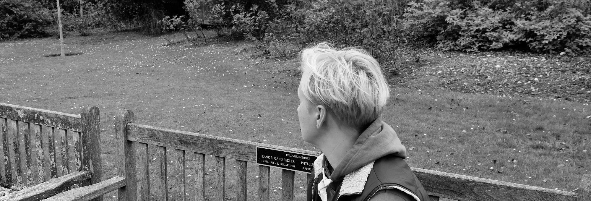 Woman turned to the side, sitting on the bench. Black and white photo