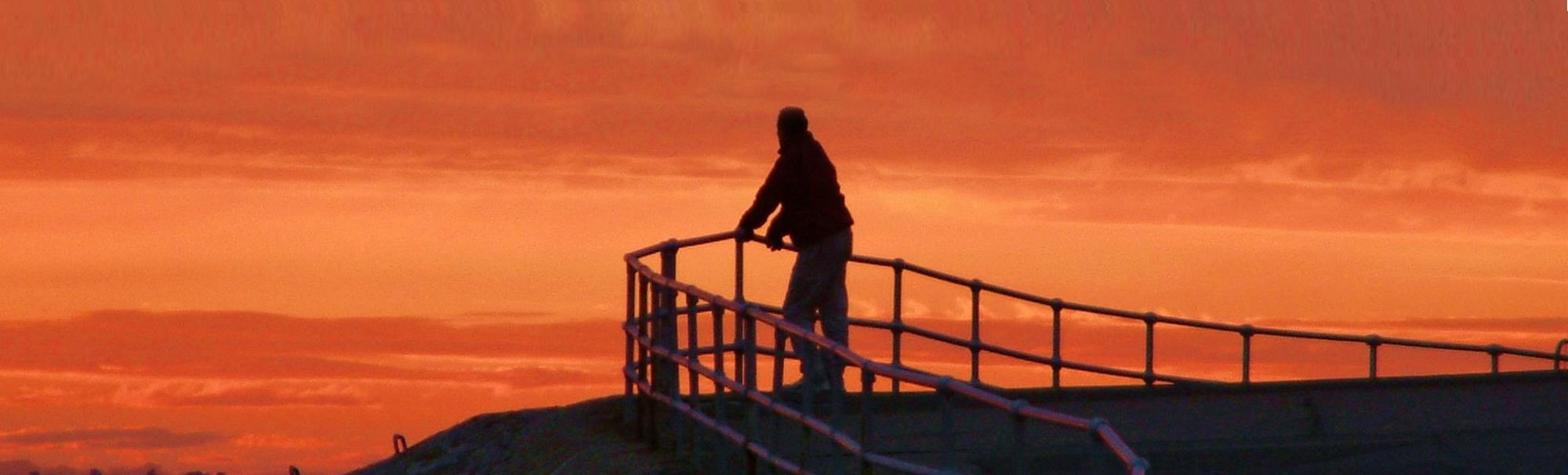 Man standing on the top of the hill, watching red sky