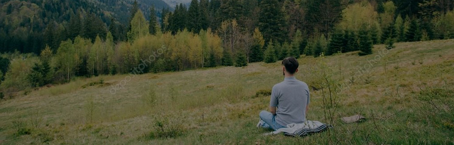 Man sitting on the grass, halway on the hill. Watching beautiful horizon - mountains, trees