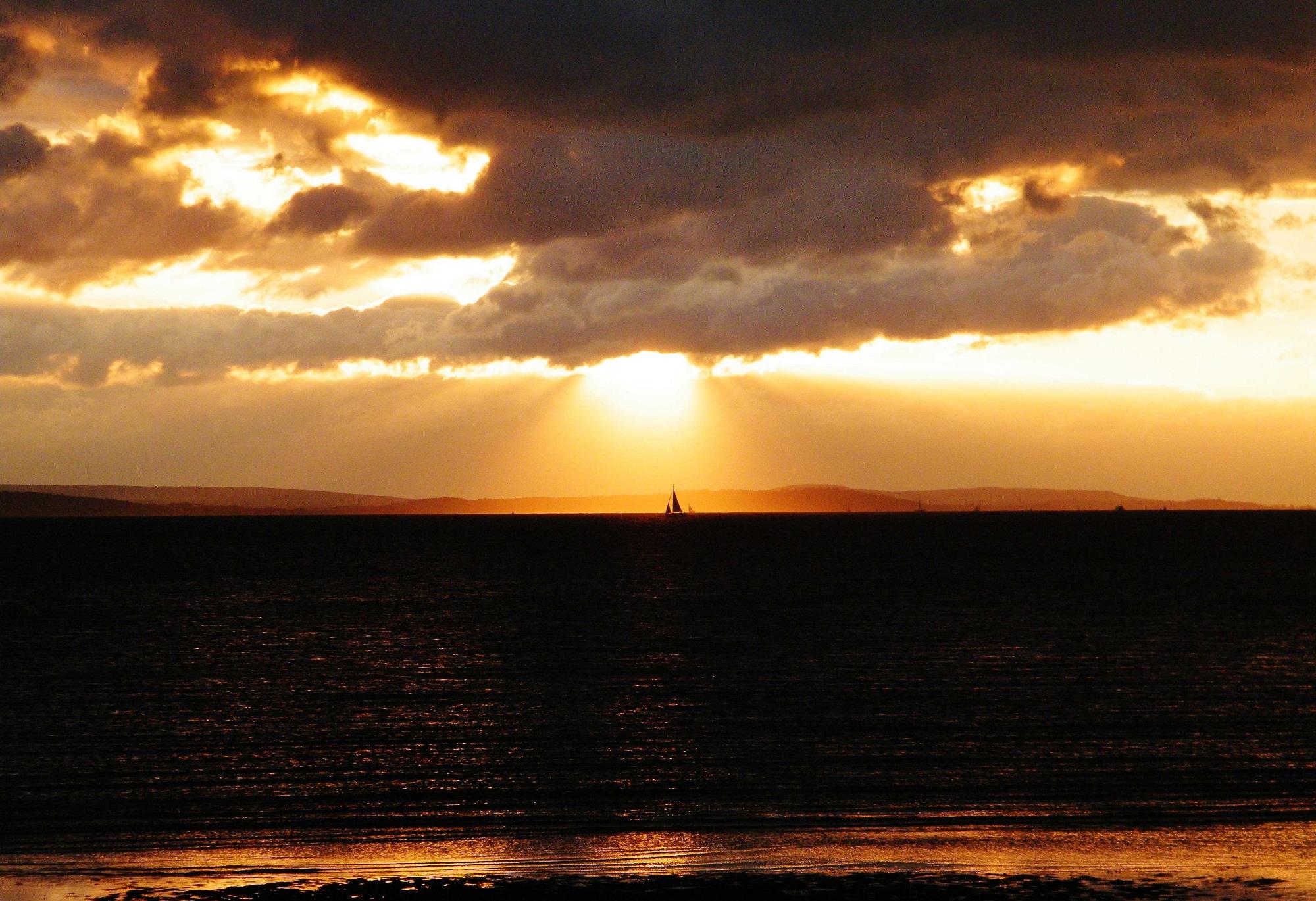 Sunrise, orange sky. Little boat in the sea. 